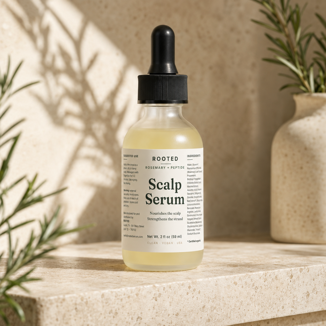 ROOTED Scalp Serum bottle on a stone ledge with rosemary